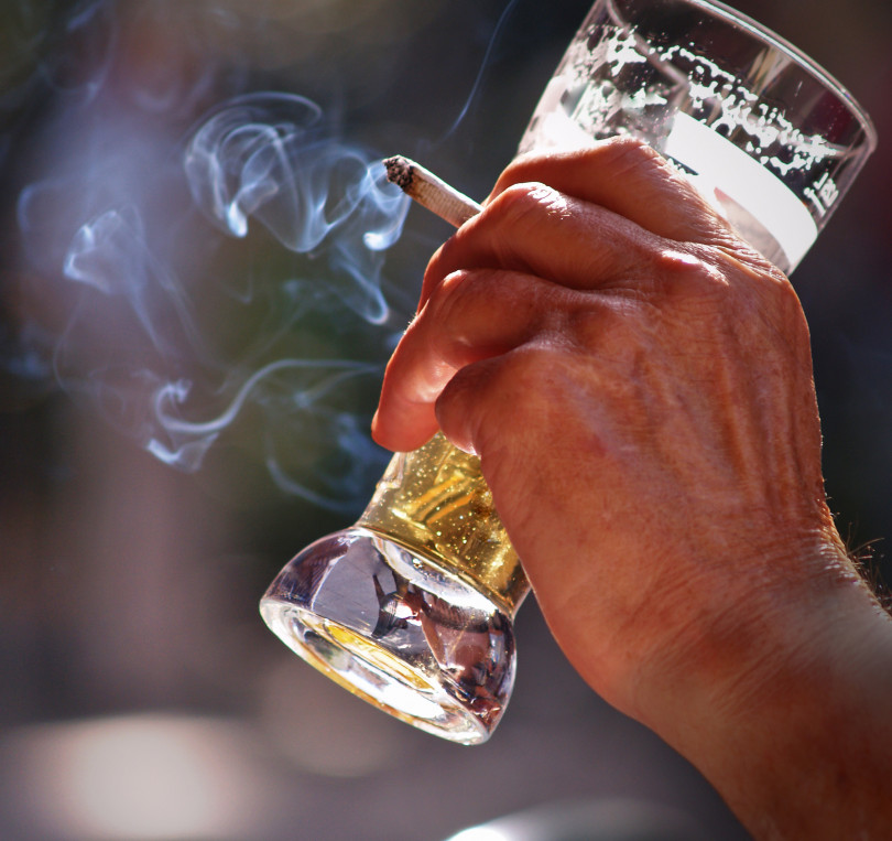 Main d'homme tenant une cigarette et un verre de bière.