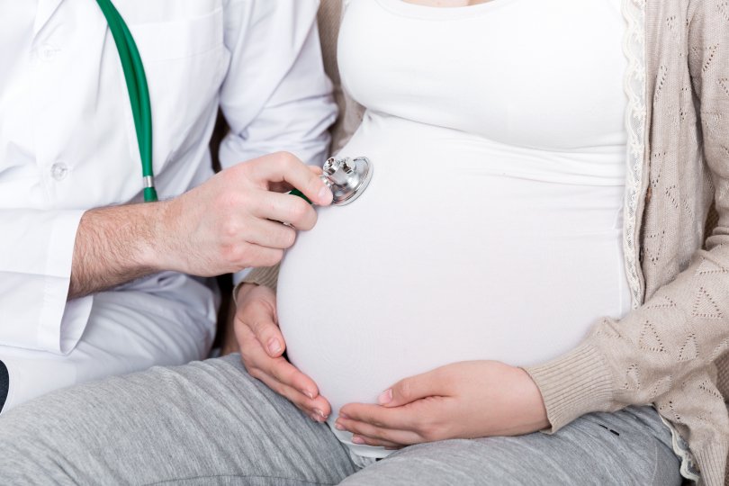 ventre de femme enceintes avec les mains d'un médecine posées dessus.