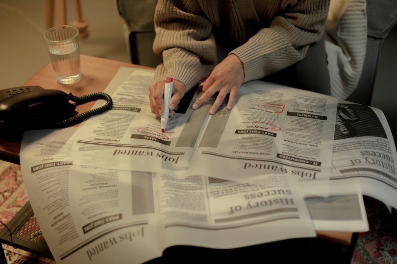 personne devant des journaux annontant une petite annonce