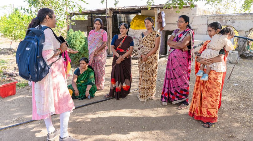 Un groupe de femmes indiennes se tiennent debout en cercle autour d'une autre femme qu'elles écoutent